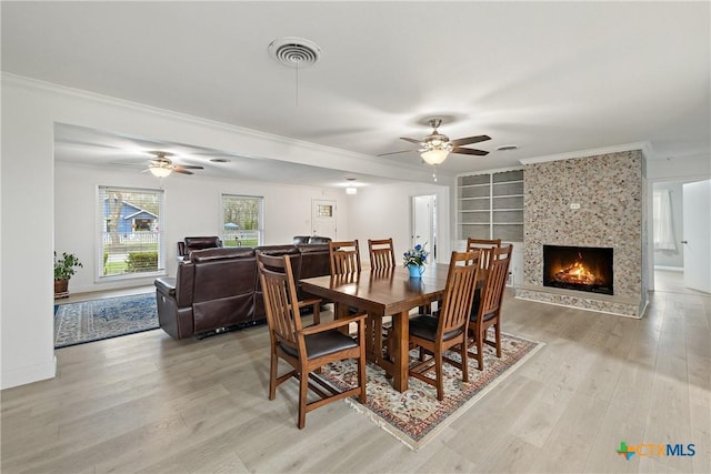 dining area with light wood-style floors, crown molding, a ceiling fan, and visible vents