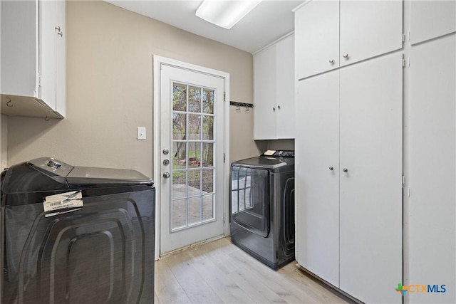 washroom featuring washer and dryer, cabinet space, and light wood finished floors