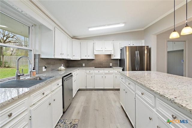 kitchen with ornamental molding, a sink, under cabinet range hood, appliances with stainless steel finishes, and vaulted ceiling