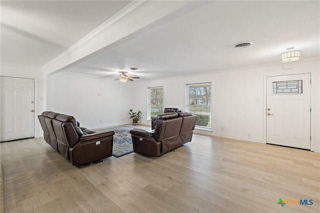 living area featuring light wood finished floors, visible vents, crown molding, baseboards, and a ceiling fan