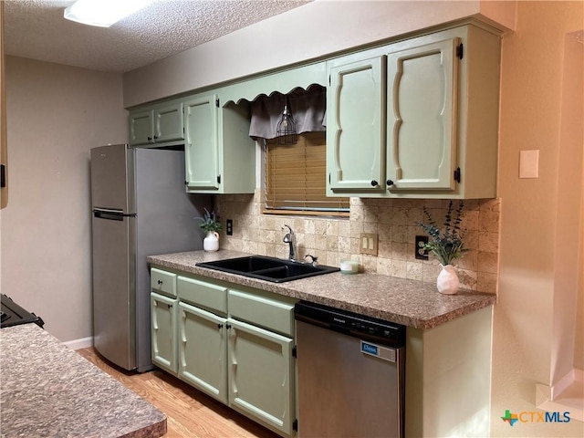 kitchen with decorative backsplash, a textured ceiling, stainless steel appliances, sink, and green cabinetry