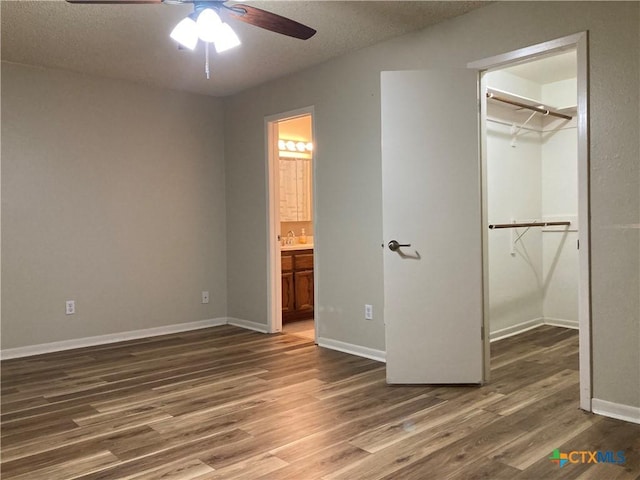 unfurnished bedroom with a walk in closet, ceiling fan, dark hardwood / wood-style floors, connected bathroom, and a closet