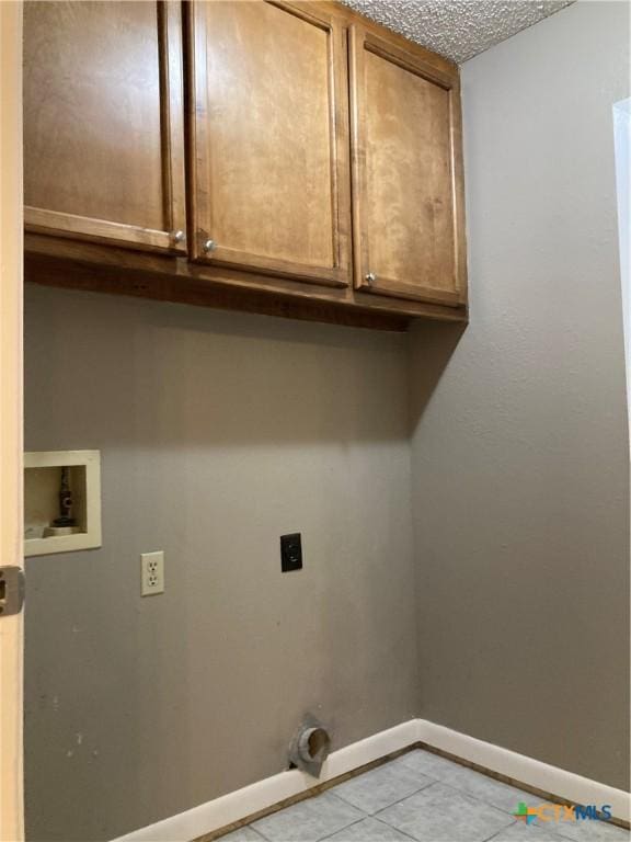 clothes washing area with cabinets, washer hookup, electric dryer hookup, a textured ceiling, and light tile patterned flooring