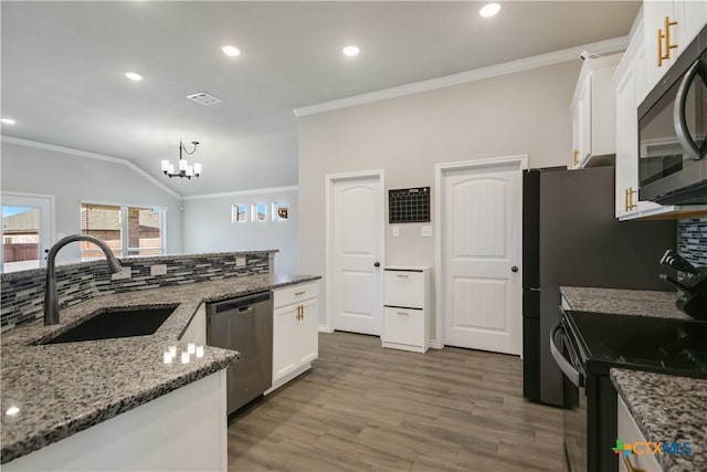 kitchen with sink, backsplash, lofted ceiling, white cabinets, and appliances with stainless steel finishes