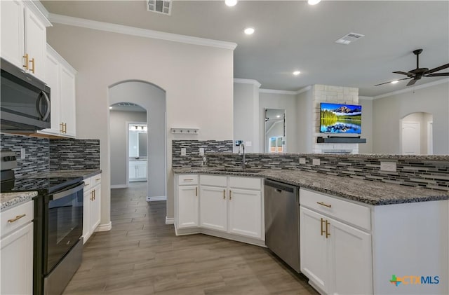 kitchen with dark stone counters, white cabinets, sink, ceiling fan, and stainless steel appliances