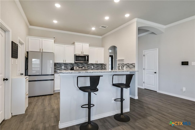 kitchen featuring decorative backsplash, a breakfast bar, white cabinets, and stainless steel appliances