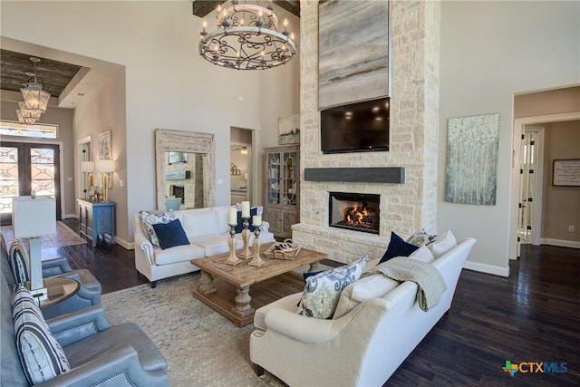 living area with a fireplace, a notable chandelier, a towering ceiling, and wood finished floors