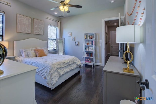 bedroom featuring dark wood-type flooring, a ceiling fan, visible vents, and baseboards