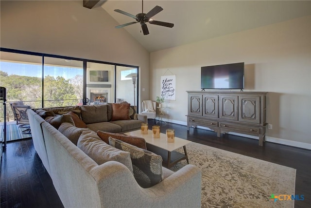 living area with dark wood-style floors, high vaulted ceiling, ceiling fan, and baseboards