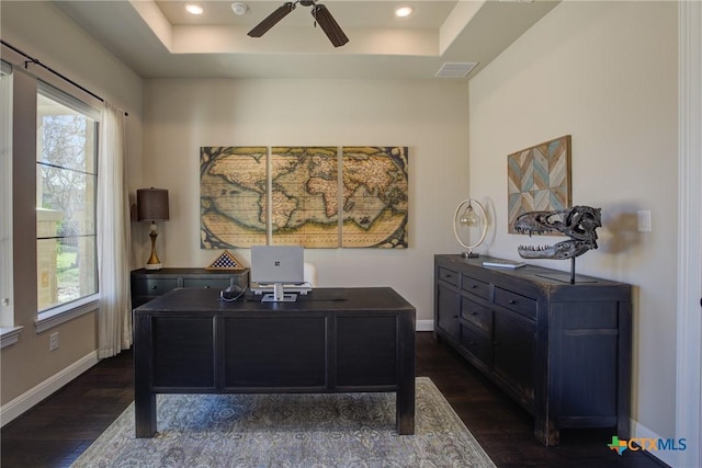 home office featuring dark wood-style floors, a tray ceiling, visible vents, and baseboards