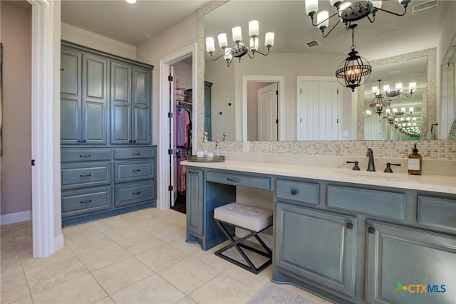 bathroom with tile patterned floors, backsplash, vanity, and a notable chandelier