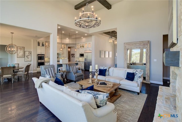 living area with a towering ceiling, baseboards, dark wood-style floors, beamed ceiling, and an inviting chandelier