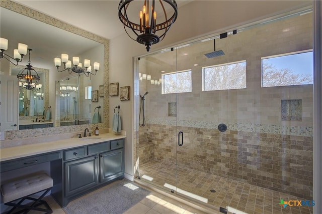 bathroom with a chandelier, tile patterned floors, vanity, a shower stall, and decorative backsplash