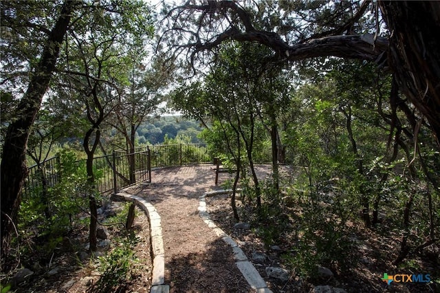 view of home's community with fence and a view of trees