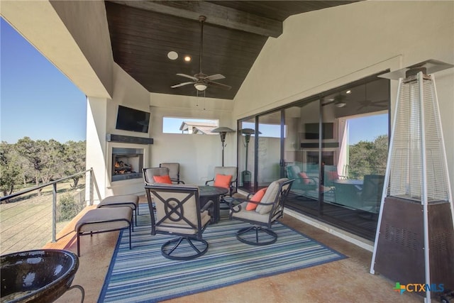 view of patio featuring a lit fireplace and a ceiling fan