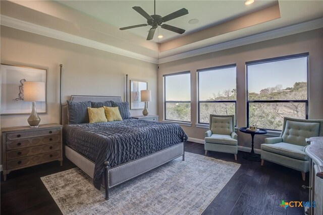 bedroom with baseboards, crown molding, a tray ceiling, and dark wood-type flooring