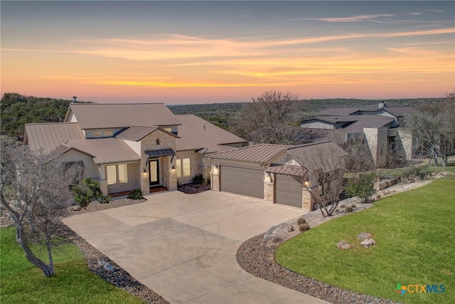 view of front of house featuring a lawn, a standing seam roof, metal roof, a garage, and driveway