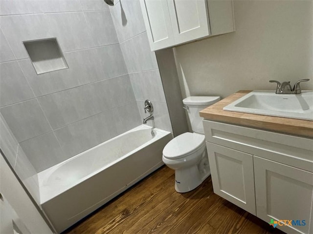 full bathroom with vanity, hardwood / wood-style floors, tiled shower / bath, and toilet