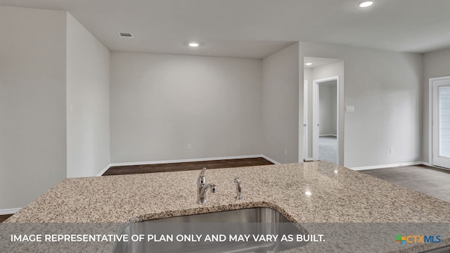 kitchen featuring sink, dark hardwood / wood-style floors, and light stone countertops