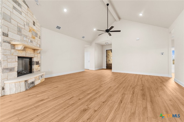 unfurnished living room featuring beam ceiling, a stone fireplace, light wood-type flooring, and high vaulted ceiling