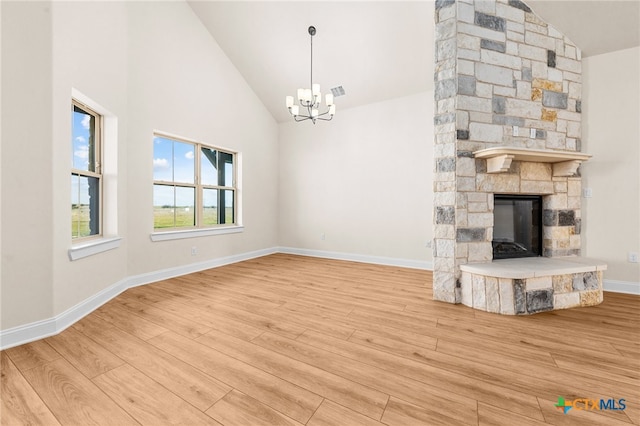 unfurnished living room featuring a fireplace, hardwood / wood-style floors, high vaulted ceiling, and a chandelier