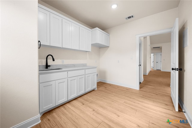 kitchen featuring white cabinets, light hardwood / wood-style floors, and sink