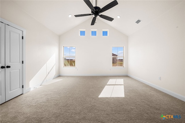 carpeted empty room with ceiling fan and high vaulted ceiling