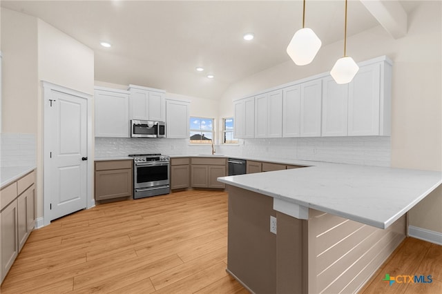 kitchen featuring kitchen peninsula, stainless steel appliances, light hardwood / wood-style flooring, hanging light fixtures, and lofted ceiling