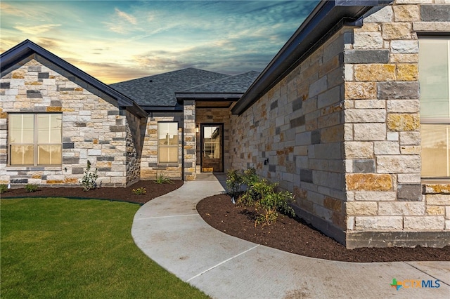 exterior entry at dusk featuring a lawn