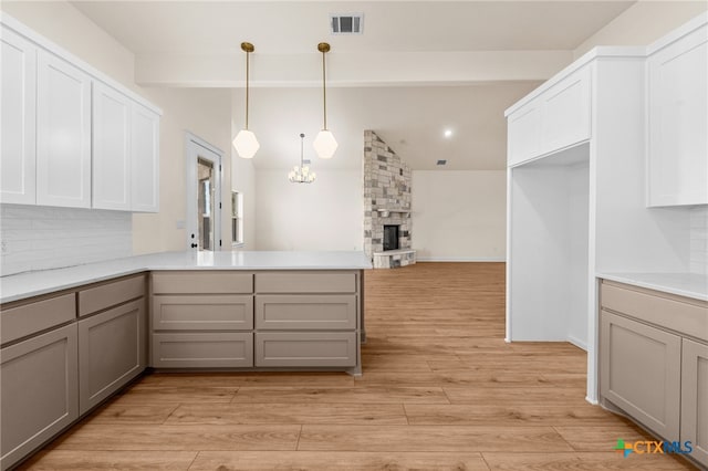 kitchen with kitchen peninsula, pendant lighting, light hardwood / wood-style flooring, and gray cabinetry