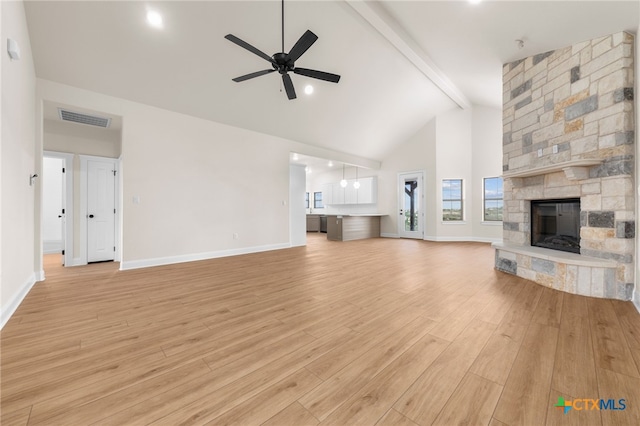 unfurnished living room with light wood finished floors, visible vents, a ceiling fan, a fireplace, and beam ceiling