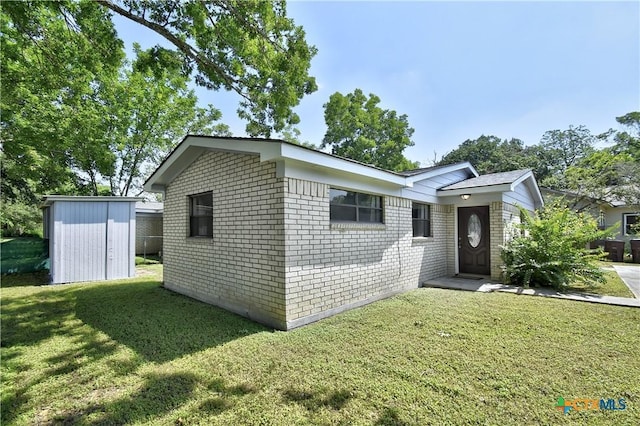 single story home featuring a front yard and a storage shed