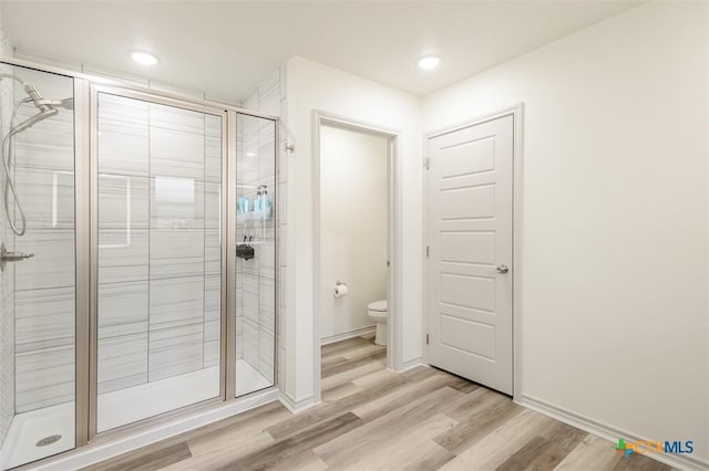 bathroom featuring recessed lighting, toilet, a shower stall, wood finished floors, and baseboards