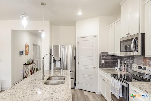 kitchen with tasteful backsplash, light stone counters, decorative light fixtures, stainless steel appliances, and white cabinetry