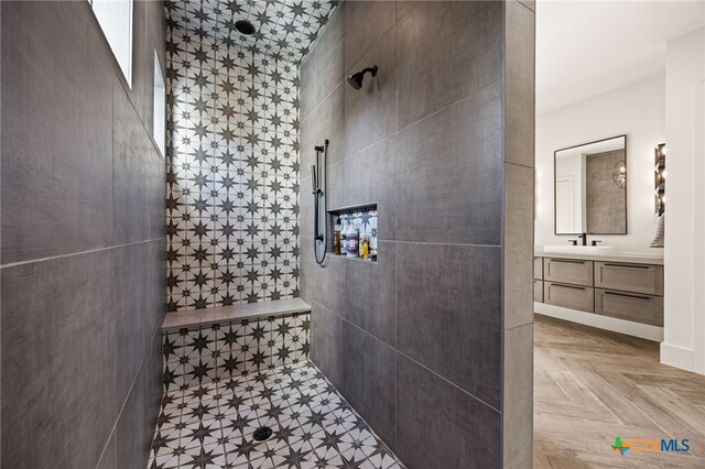 bathroom featuring tile walls, tiled shower, parquet floors, and vanity