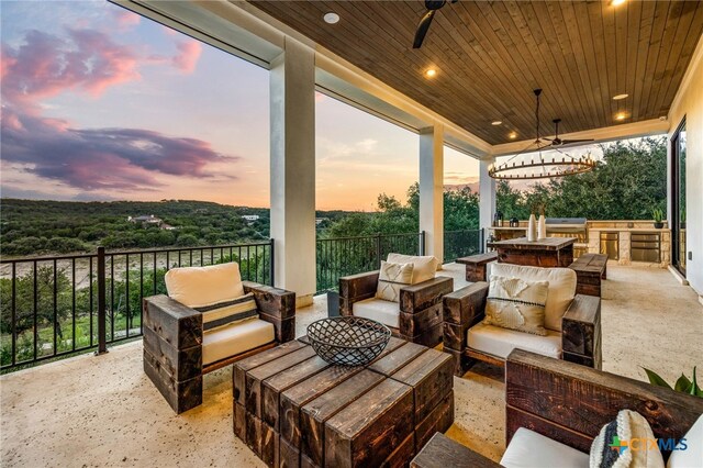 patio terrace at dusk featuring ceiling fan and an outdoor living space with a fire pit