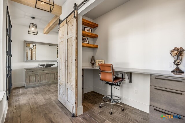 home office featuring dark hardwood / wood-style flooring, a barn door, built in desk, and beam ceiling