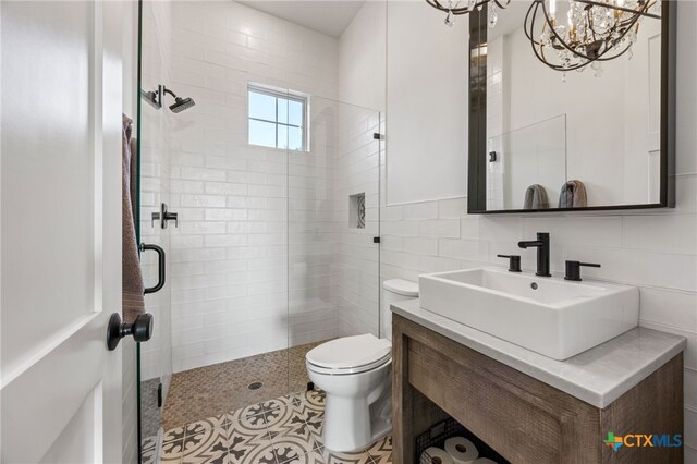 bathroom featuring walk in shower, vanity, a notable chandelier, toilet, and tile walls