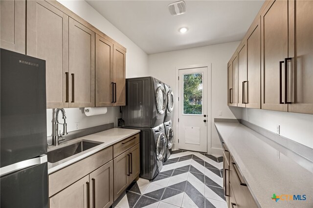 laundry area featuring sink, stacked washer and clothes dryer, and light tile patterned flooring