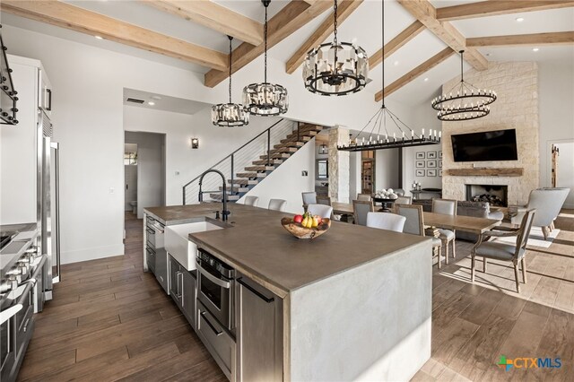 kitchen with dark hardwood / wood-style flooring, sink, pendant lighting, appliances with stainless steel finishes, and white cabinetry