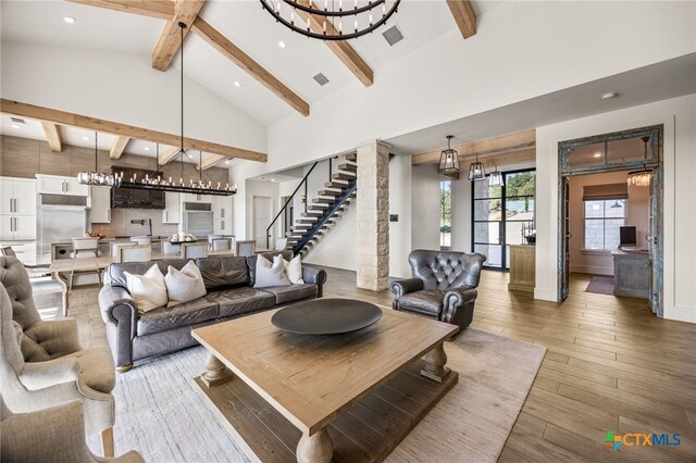 living room with hardwood / wood-style floors, beam ceiling, a chandelier, and high vaulted ceiling