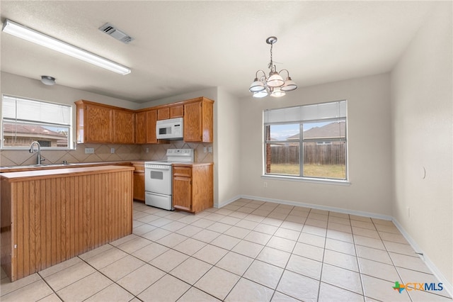 kitchen with tasteful backsplash, white appliances, a notable chandelier, and plenty of natural light