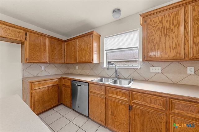 kitchen featuring tasteful backsplash, stainless steel dishwasher, sink, and light tile patterned floors