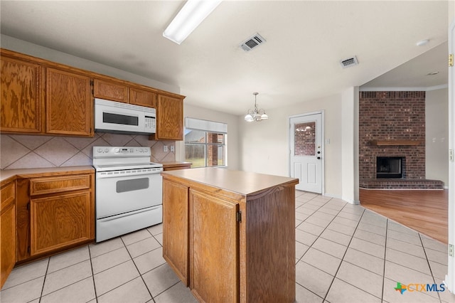 kitchen with a center island, hanging light fixtures, a notable chandelier, light tile patterned floors, and white appliances