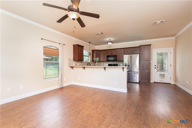 4360 Flint Oak Dr, Belton, TX 76513 - kitchen with stainless steel fridge, black microwave, dark wood finished floors, light countertops, and ornamental molding