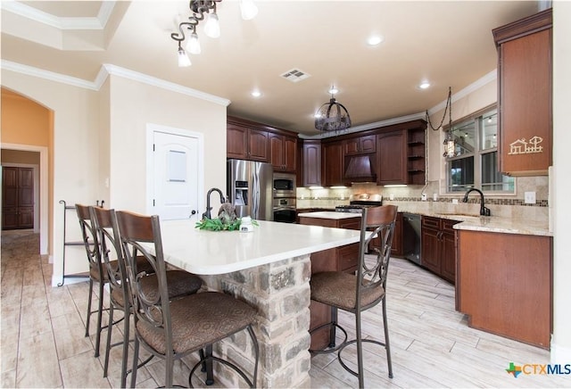 4360 Flint Oak Dr, Belton, TX 76513 - kitchen featuring appliances with stainless steel finishes, a kitchen island with sink, a sink, a kitchen bar, and crown molding