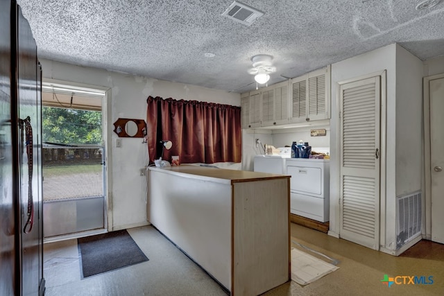 kitchen with a textured ceiling, kitchen peninsula, washer and clothes dryer, and ceiling fan