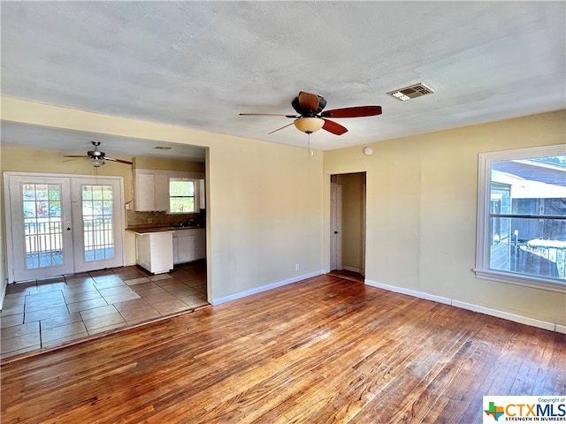 spare room featuring ceiling fan, a textured ceiling, light wood-type flooring, and french doors