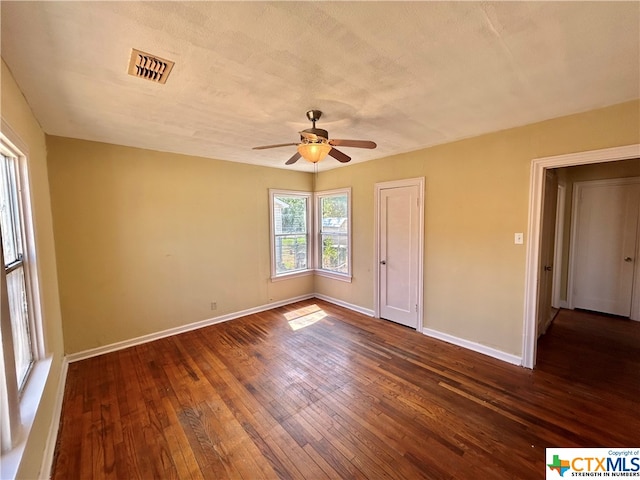 empty room featuring a textured ceiling, dark wood-type flooring, and ceiling fan