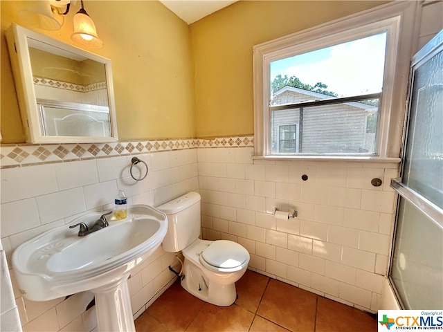 bathroom with tile walls, toilet, combined bath / shower with glass door, and tile patterned floors